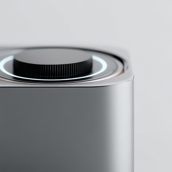 Close-up of a silver brushed-metal device with a dark knurled dial encircled by a glowing white ring against a plain white background