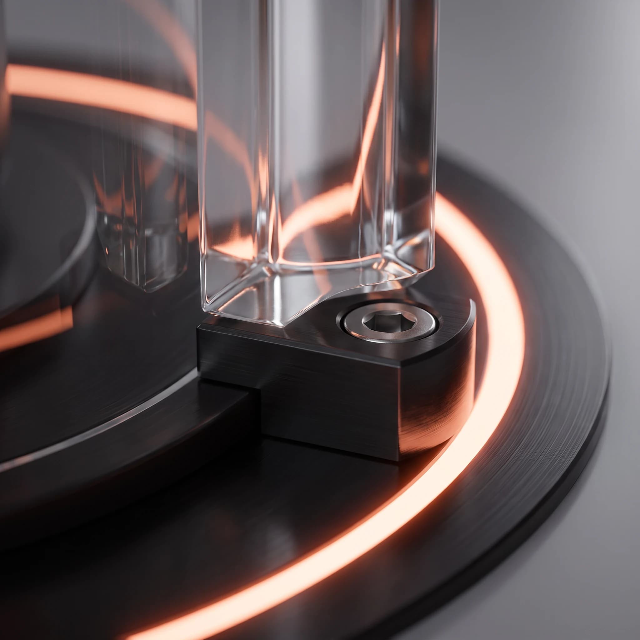 Close view where a clear glass pillar post meets the base plate, its machined mounting block and hex fastener sharp in the foreground while the base's glowing coral ring sweeps behind and refracts through the glass